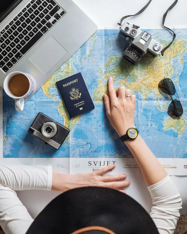 Illustrationsbild: reseplanering med karta, kamera, dator och pass.