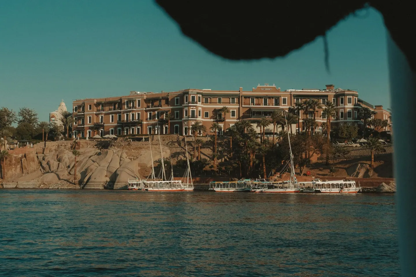 Hotell och båtar vid Nilens klippiga strand i Aswan.