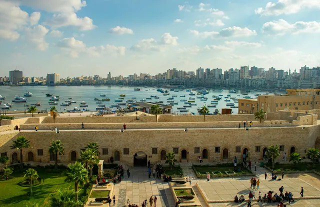 Badstrand och citadellet Qaitbay vid havet i Alexandria